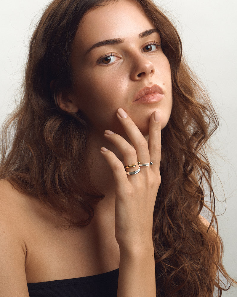Female model wearing two Saga Open Anchor Rings in silver and one Saga Open Anchor Ring in gold.