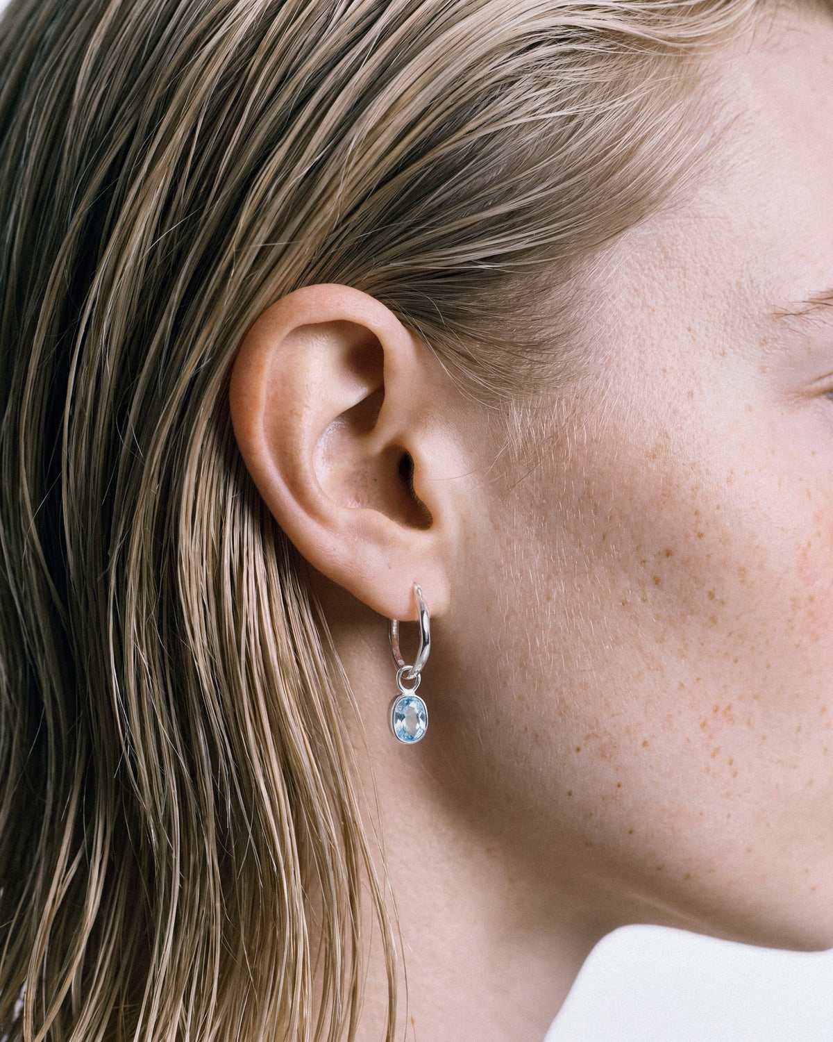 Arishi Ideal Hoops in silver with Blue Topaz, worn by a model — close-up, for COLD SKIN.