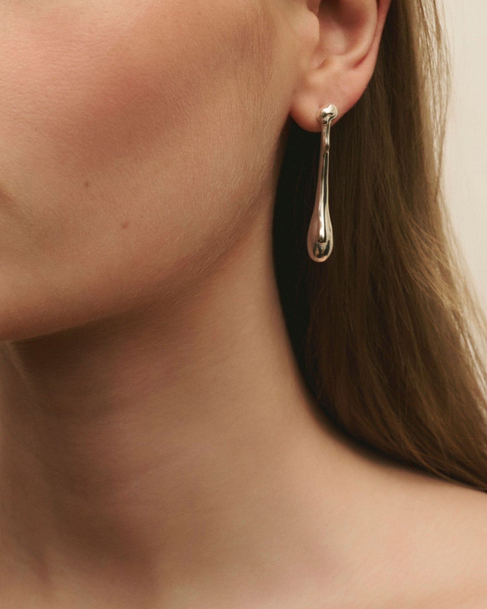 Close-up of women wearing Louis Abel Cadendo Earrings in silver.