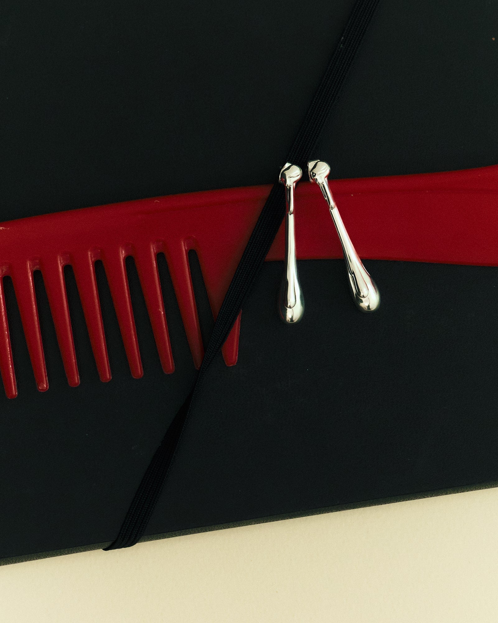 Louis Abel Cadendo Earrings in silver hanging on a red comb.