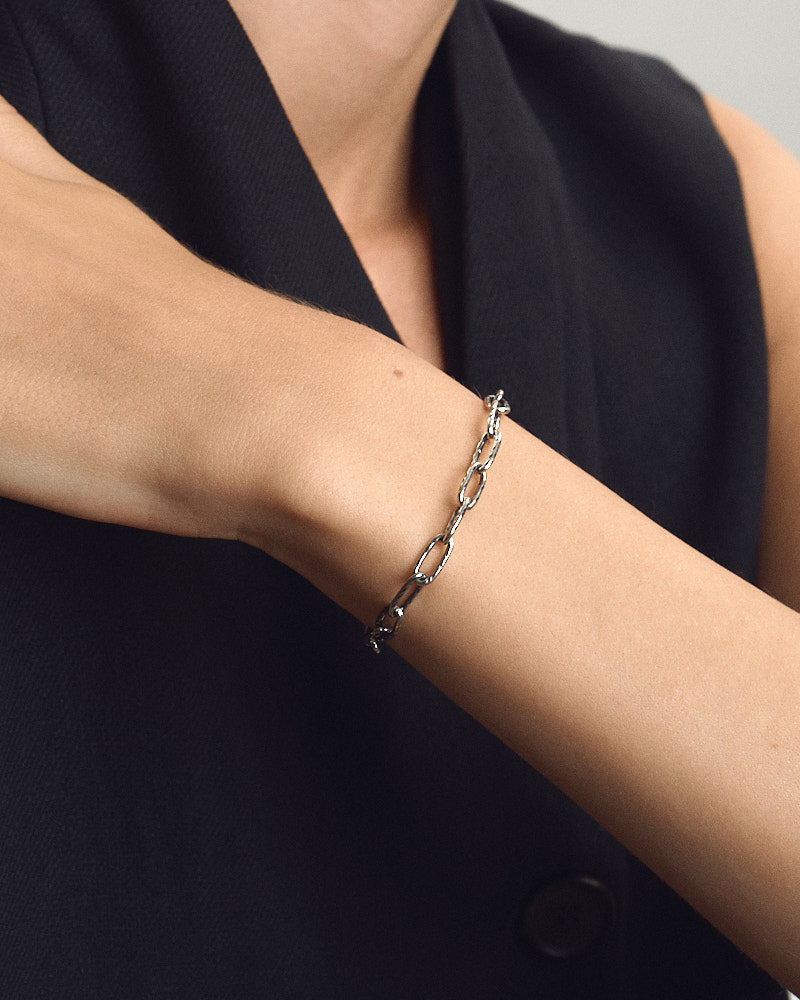 Female model wearing SEASTER Swell Bracelet in Silver, the elongated oval-link silver chain around her wrist, for COLD SKIN.