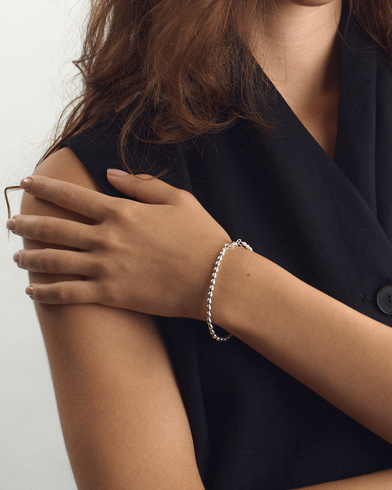 Female model wearing PEARL NAKED Lola Bracelet in Silver & Pearls, hand resting on the shoulder showing the beaded silver bracelet, for COLD SKIN.