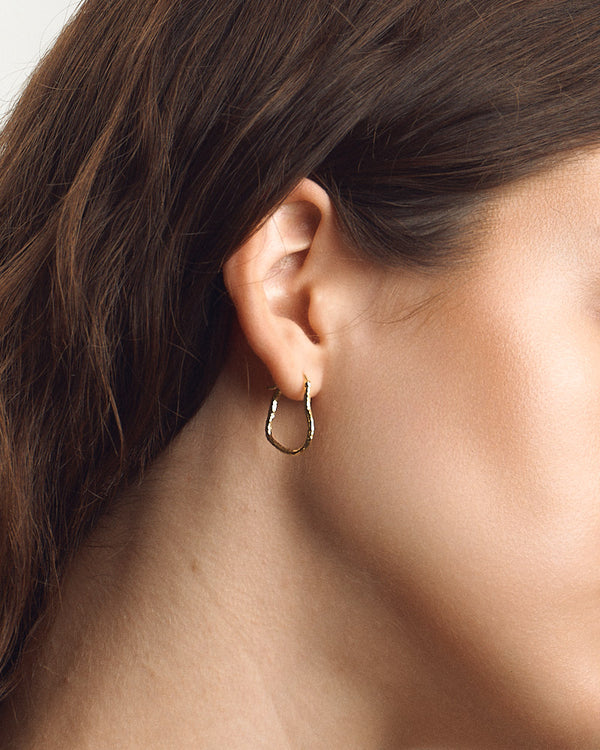 Female model wearing SEASTER Mini Bawa Hoop in Gold, the small textured gold hoop on her earlobe — close-up, for COLD SKIN.