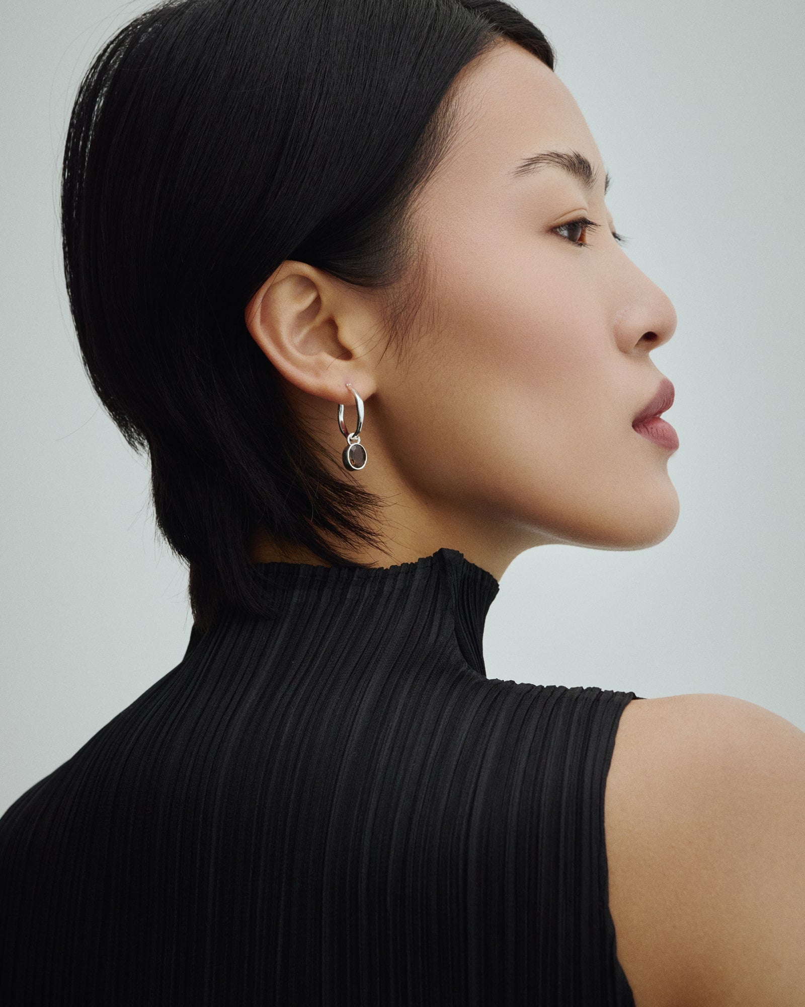 Weibliches Model trägt Arishi Ideal Hoops in Silber mit Rauchquarz.