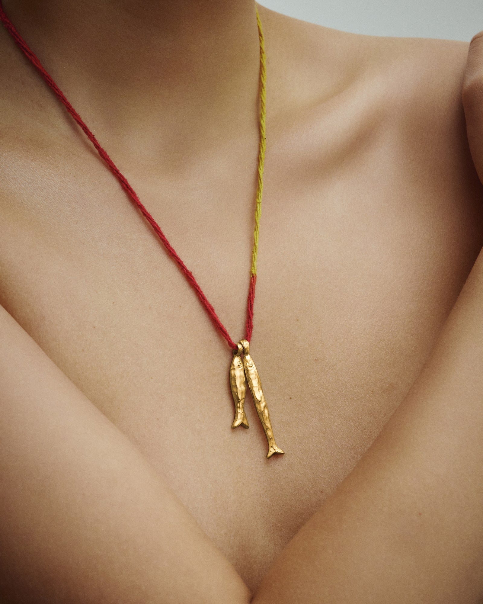 Female model wearing Éclis Asho Fish Amulet in gold.