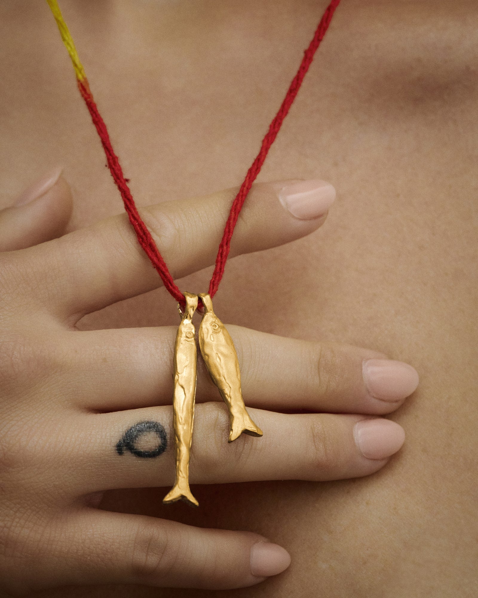 Female model wearing Éclis Asho Fish Amulet in gold.