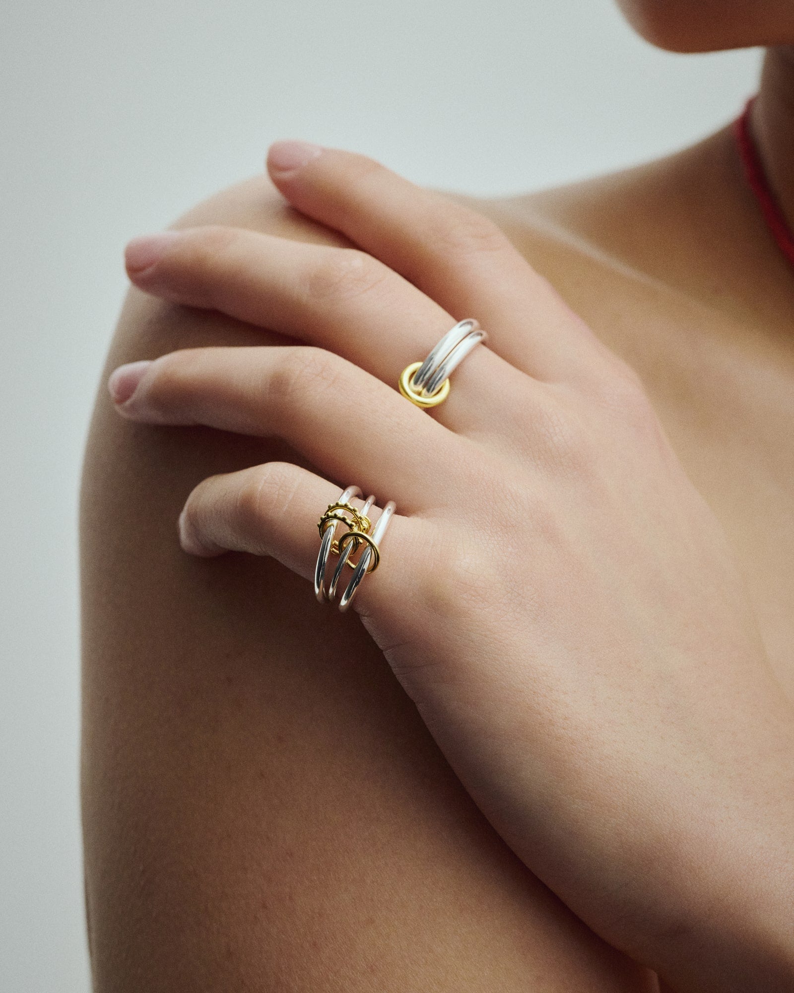 Female Model wearing Éclis Dua Ring and Triple Ring in silver with gold details.