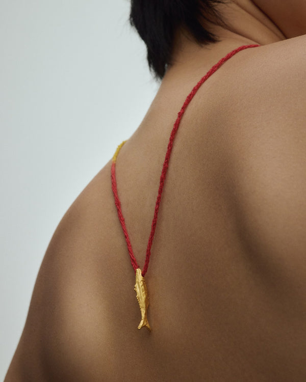 Female model wearing Éclis Oona Fish Amulet in gold.