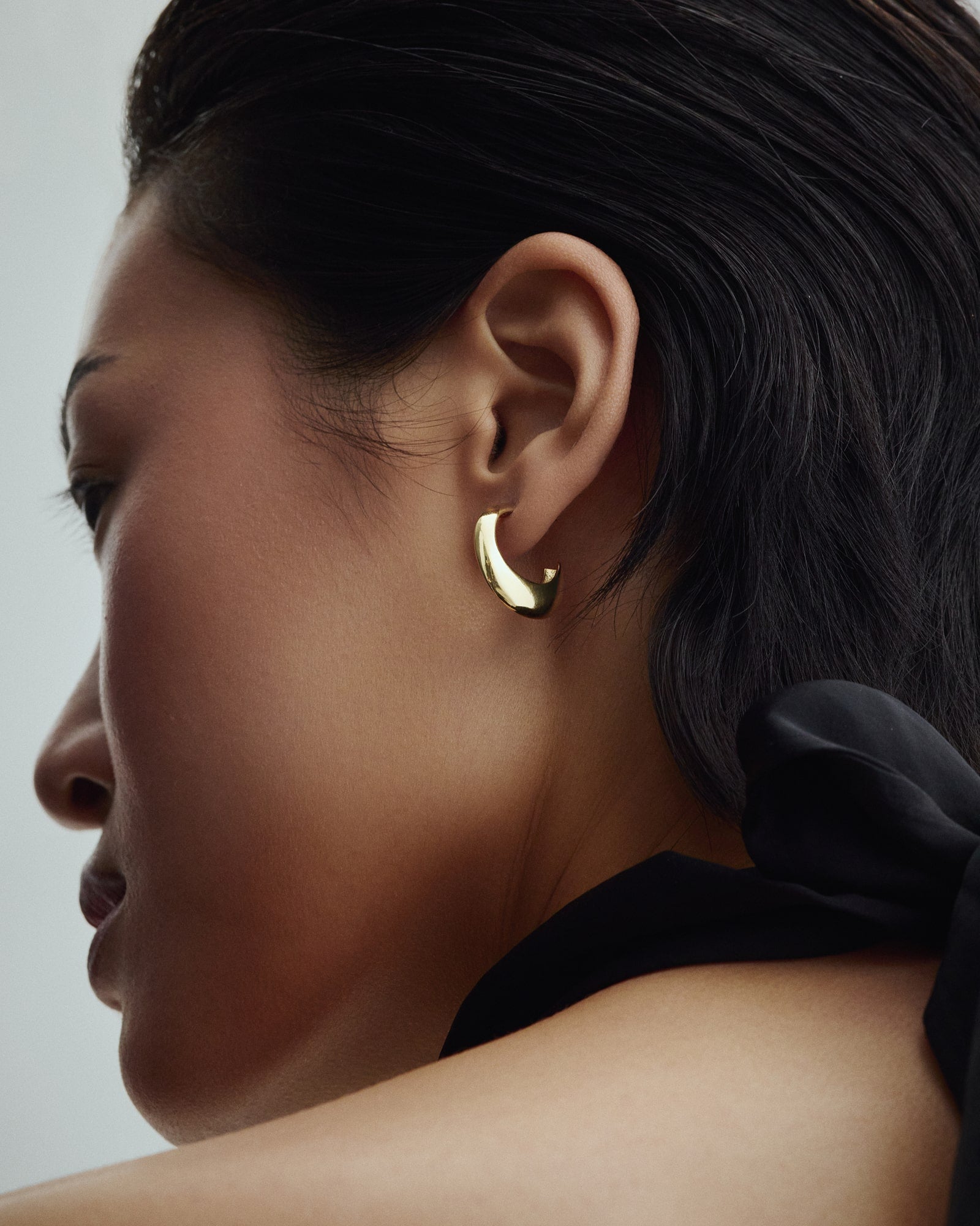 Female model wearing Saga Anchor Hoops in gold.