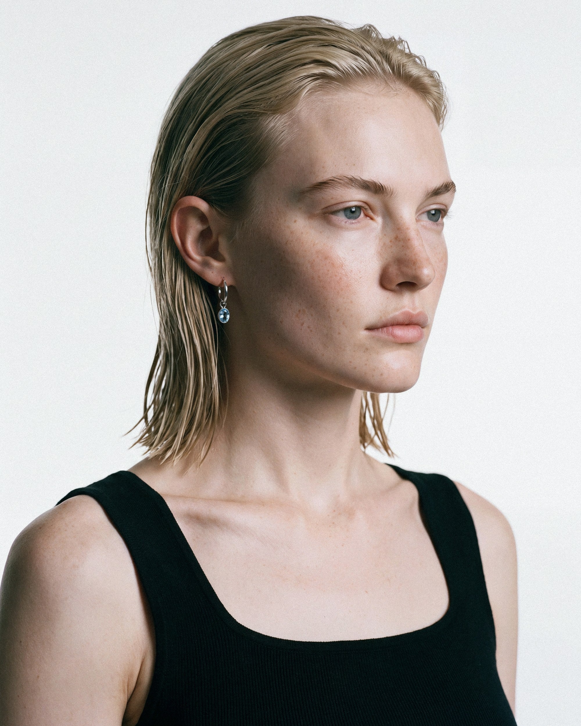 Arishi Ideal Hoops in silver with Blue Topaz, worn by a model, for COLD SKIN.