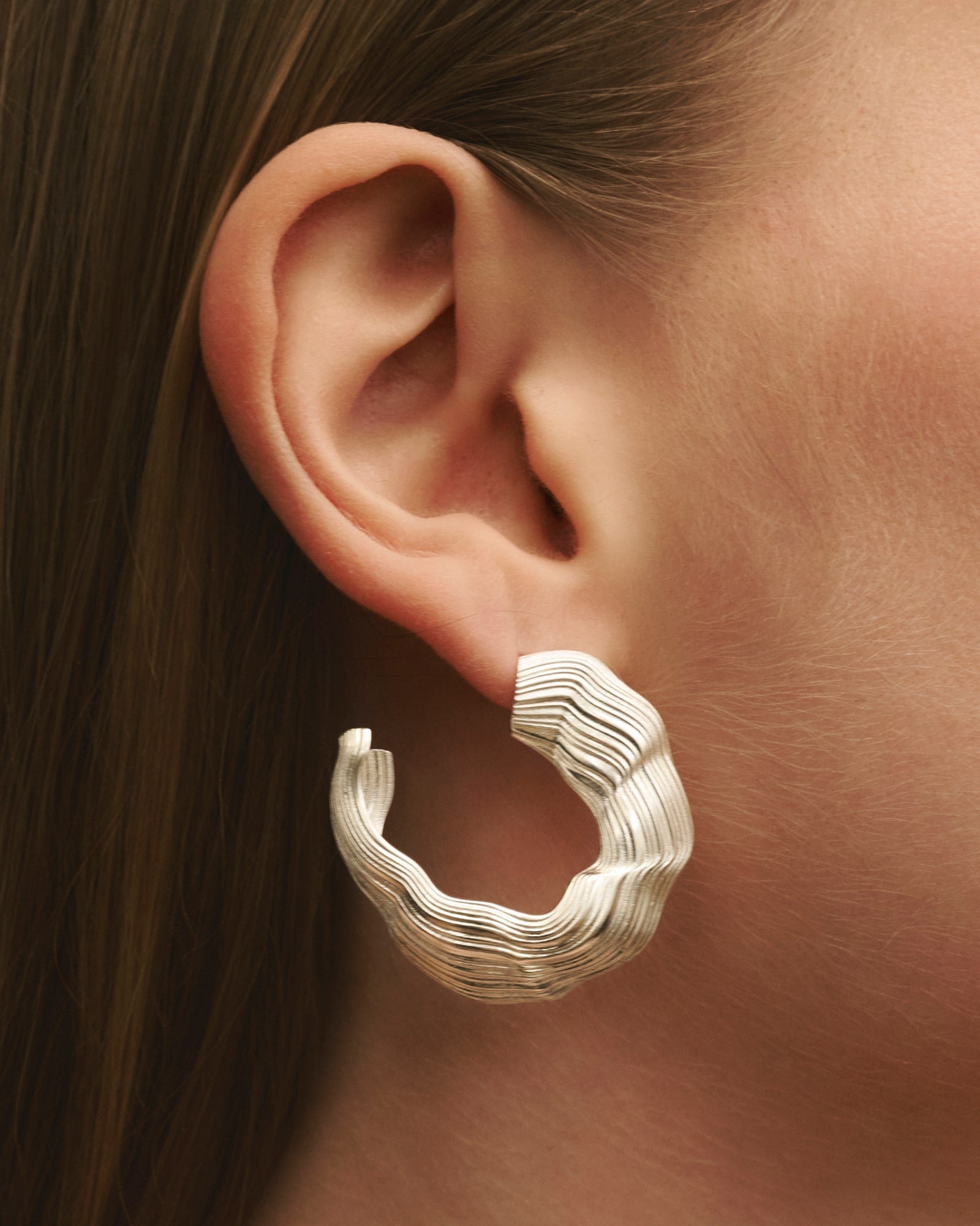 Female model wearing Louis Abel Abluvio earrings in silver.