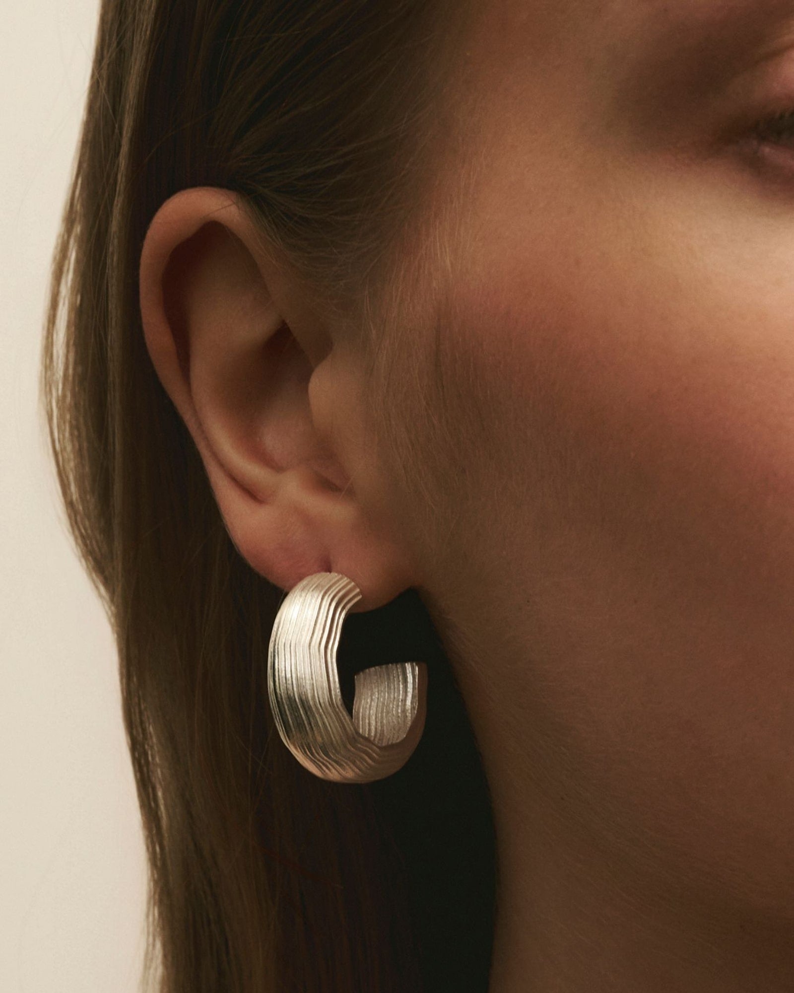 Women wearing Louis Abel Abluvio Mid Hoops in silver.