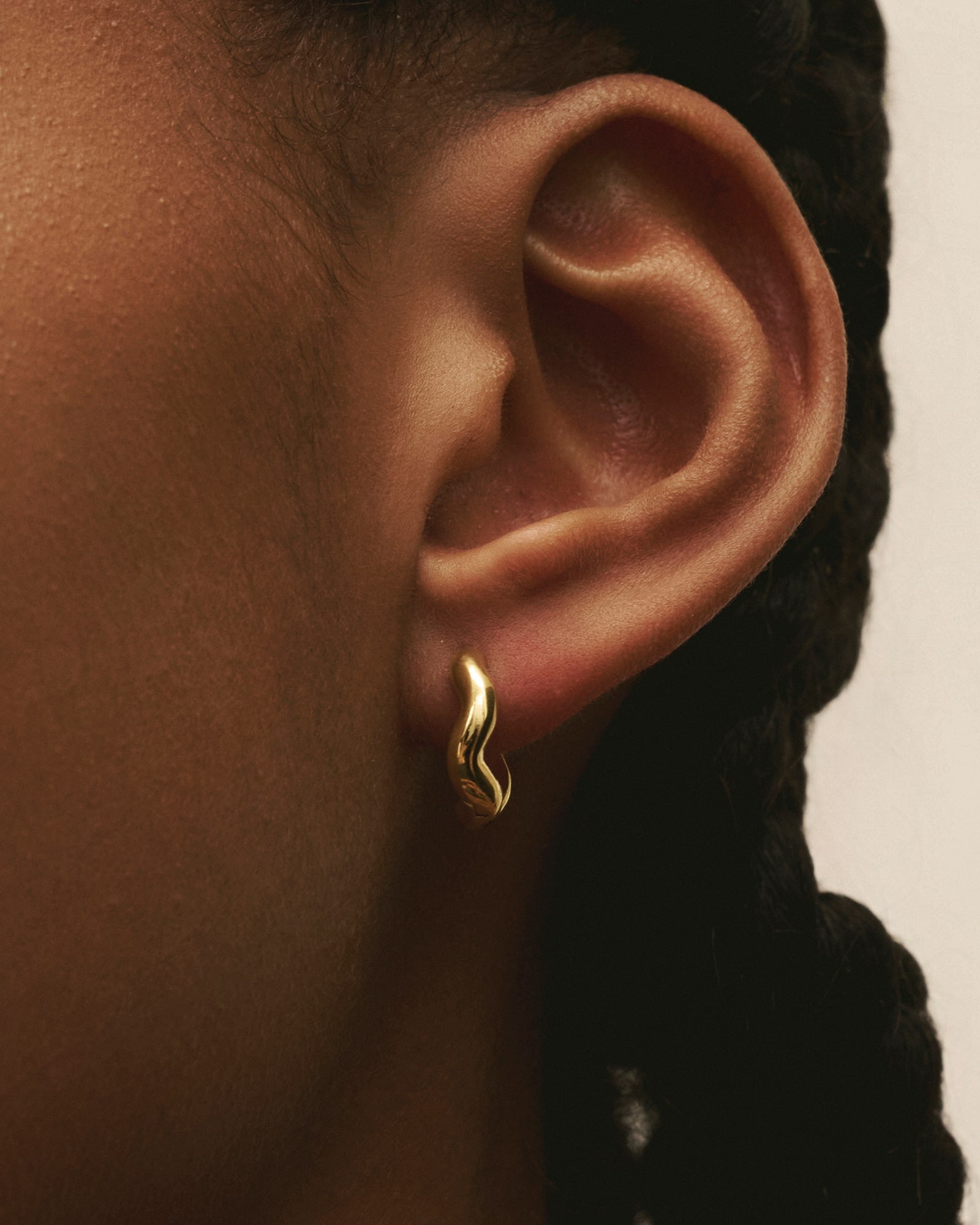 Close-up of women wearing Louis Abel Aurea Polished Mini Hoops in gold.
