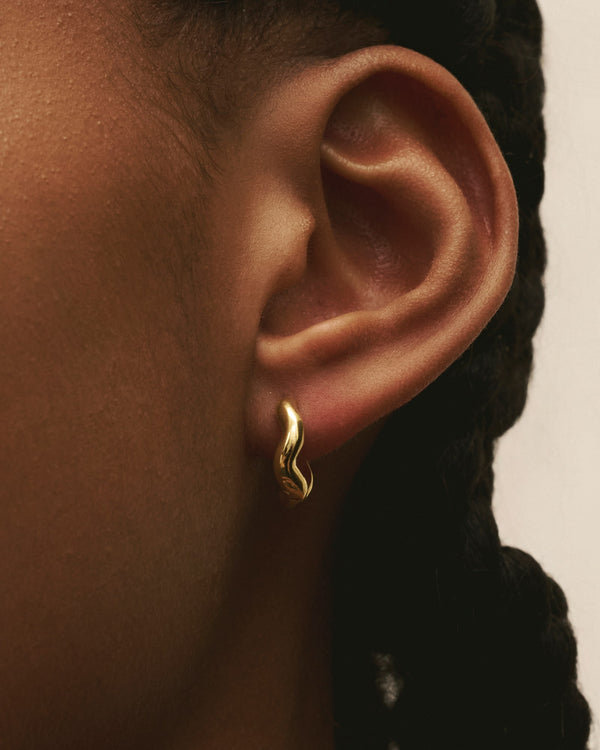 Primer plano de una mujer con los Louis Abel Aurea Polished Mini Hoops en oro.