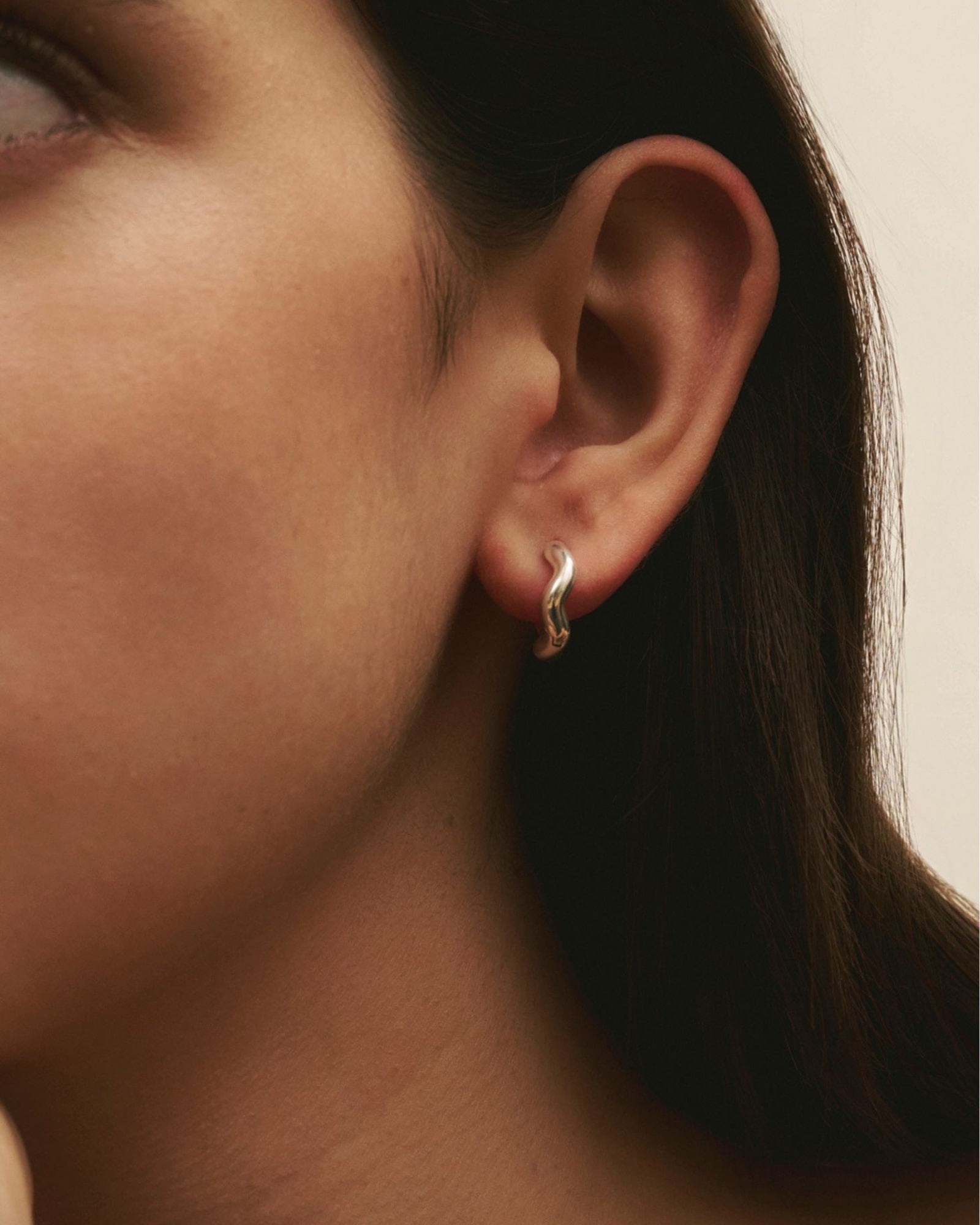 Close-up of women wearing Louis Abel Aurea Polished Mini Hoop in silver.