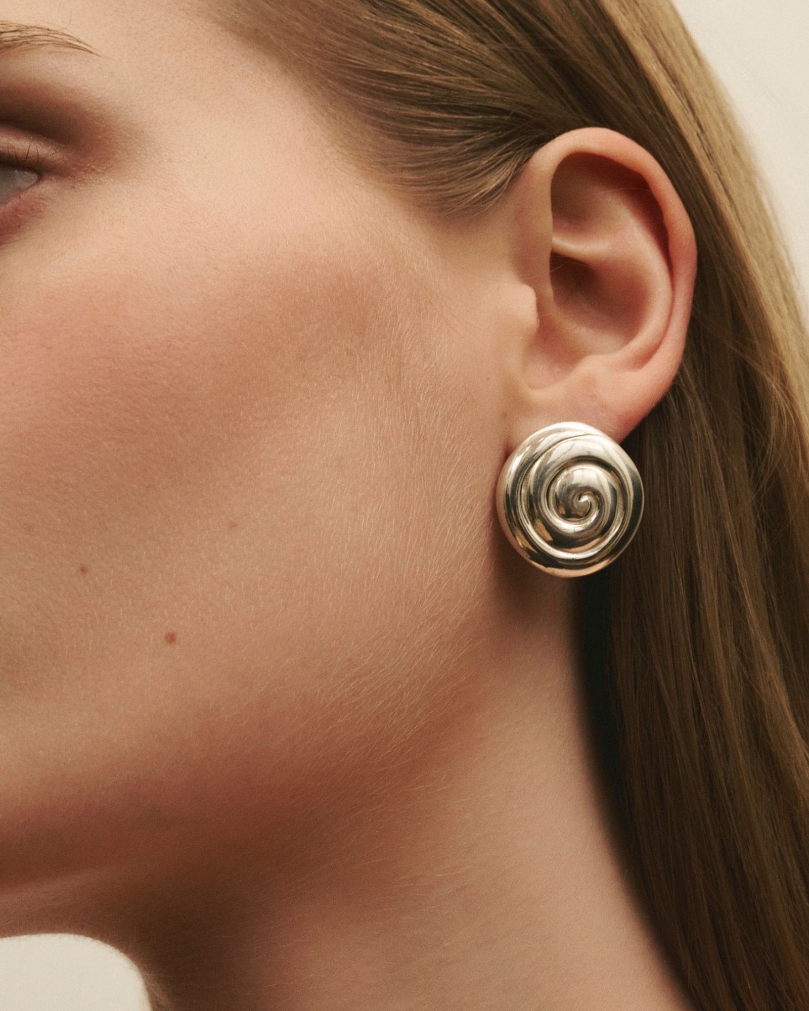 Close-up of women wearing Louis Abel Uzu Mid Earrings in silver.