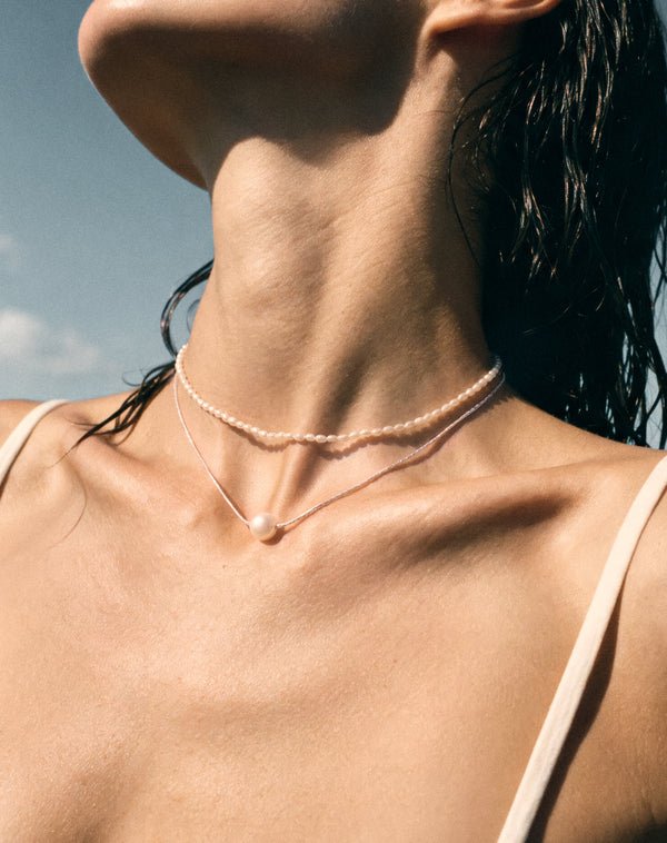 Close-up of model wearing Pearl Naked Cute Choker and Sunny Dust Necklace in silver.