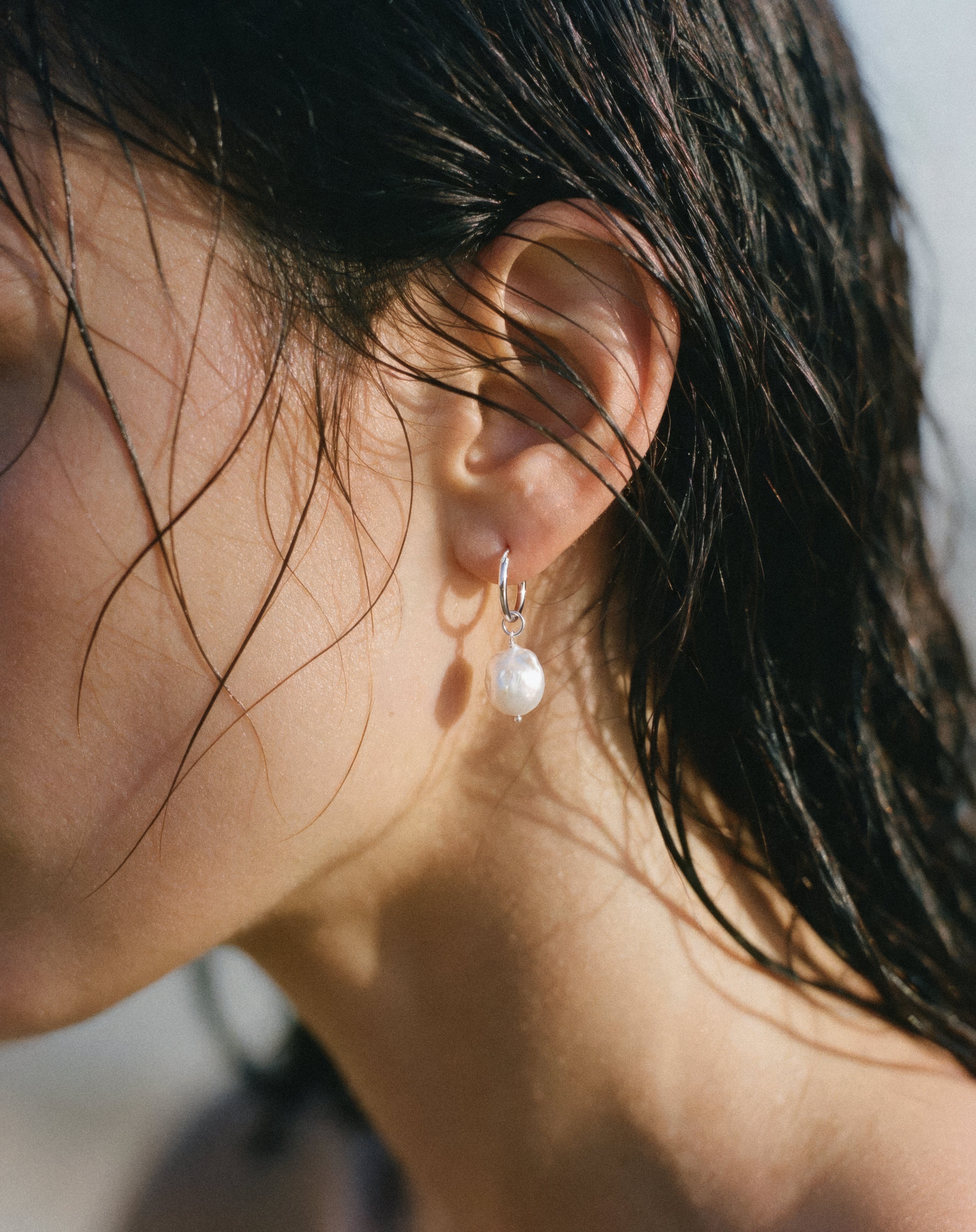 Close-up of model wearing Pearl Naked Mermaid Tear Earrings in silver.