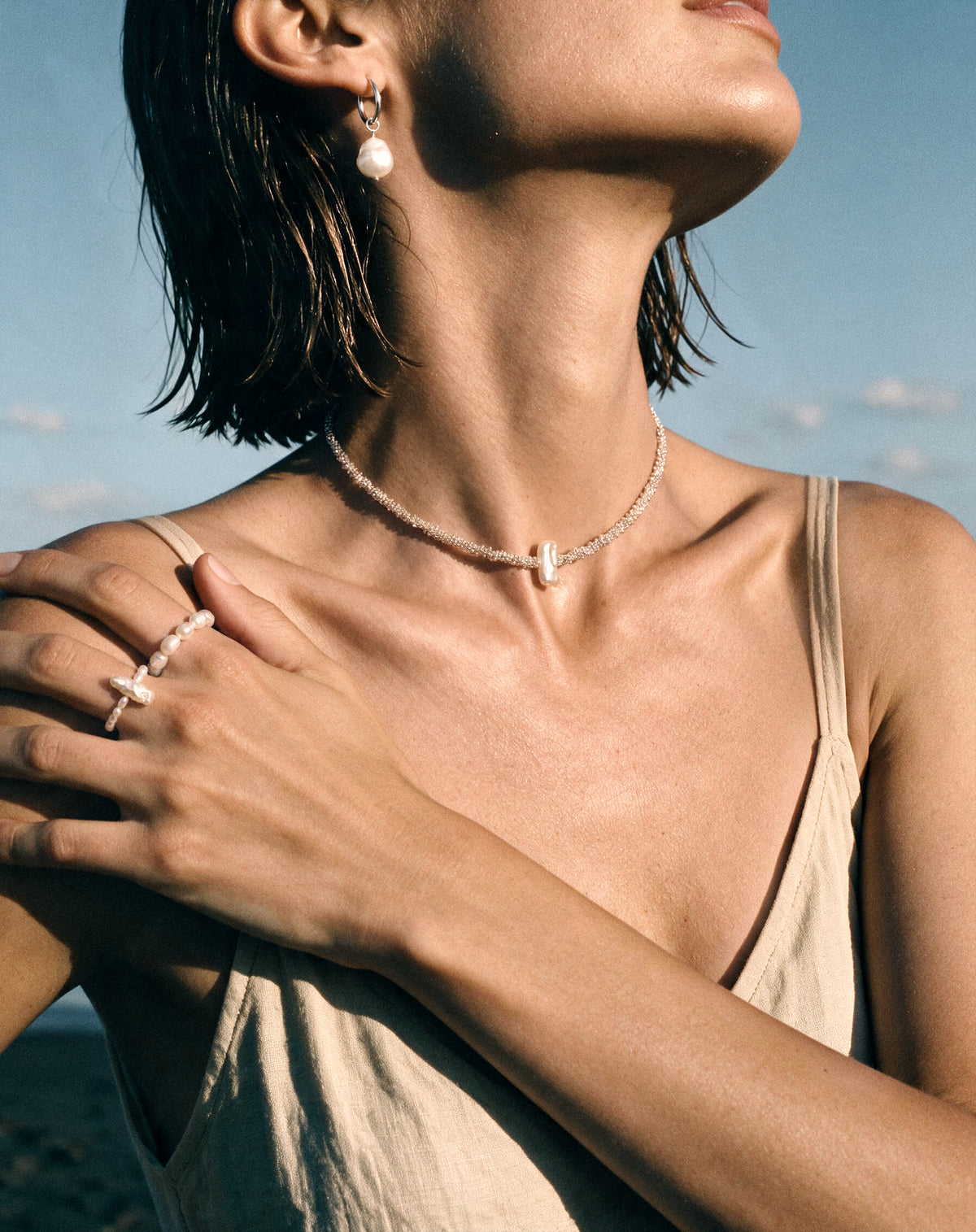 Close-up of women wearing Pearl Naked Reef Pearl Choker, Mermaid Tear Earrings, Big Rice and August Ring.