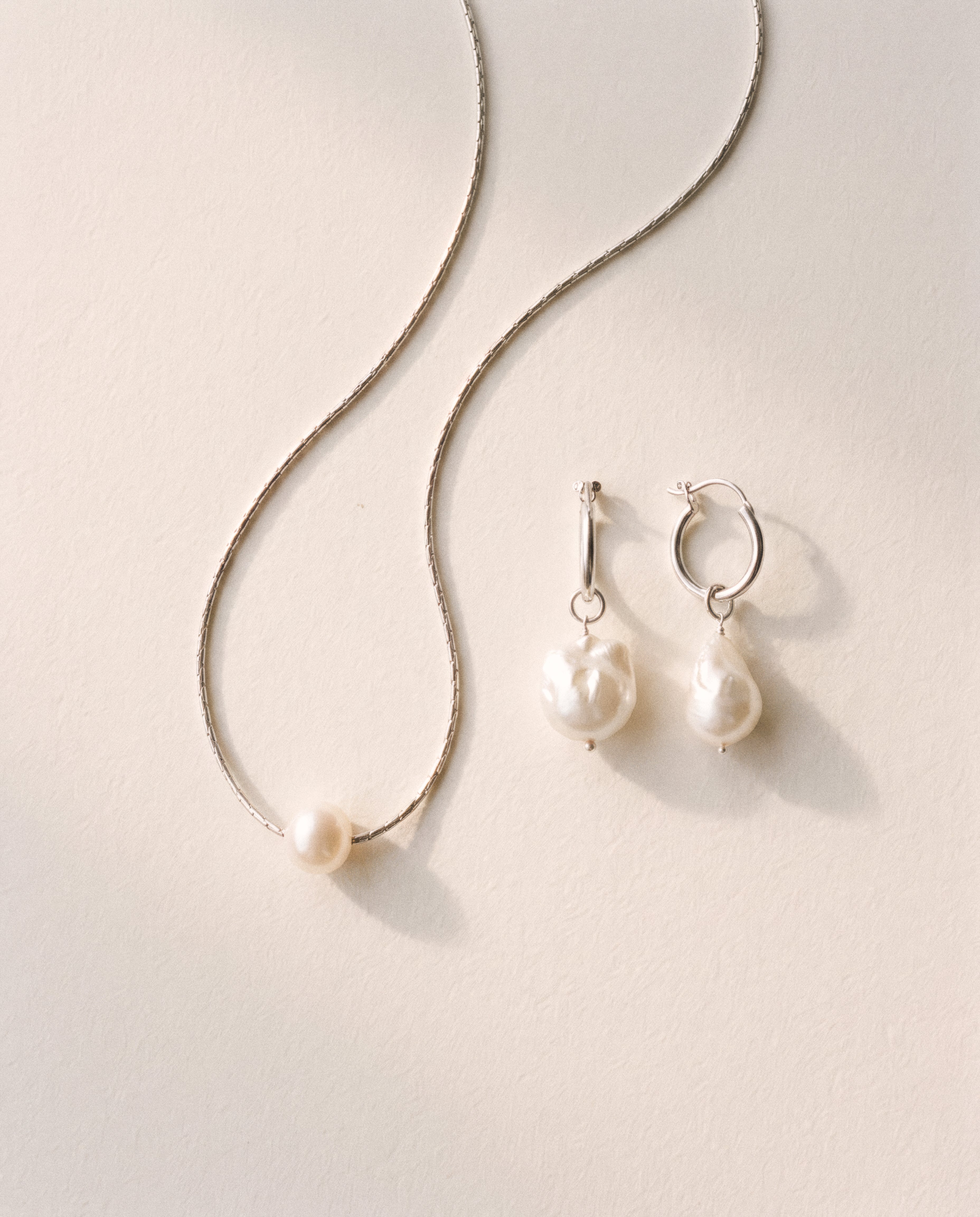 Close-up of Pearl Naked Mermaid Tear Earrings in silver.